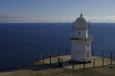 Lighthouse by sea against sky