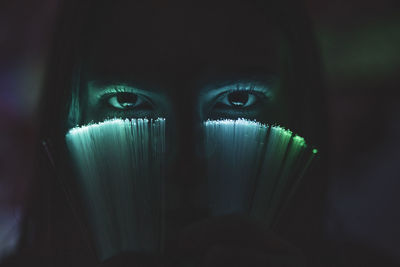 Close-up portrait of young woman holding illuminated fiber optic