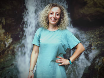 Portrait of smiling young woman standing on rock