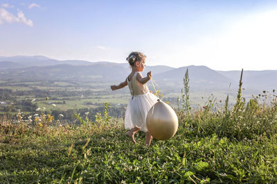 Woman with arms raised on mountain against sky