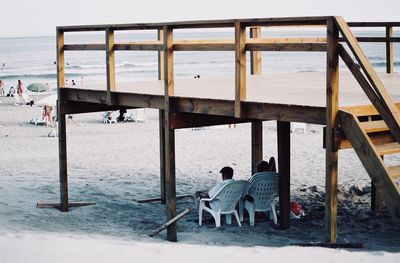 Rear view of people sitting on chairs at beach