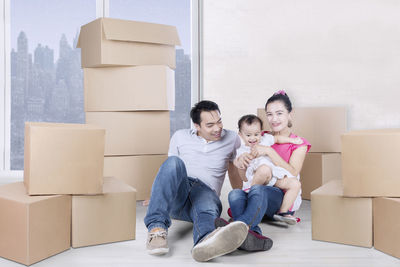 Happy parents with daughter sitting in new home