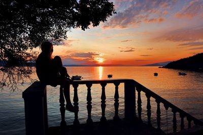 Silhouette woman looking at sea against sky during sunset