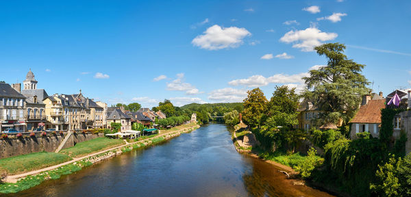 View of buildings by river against cloudy sky