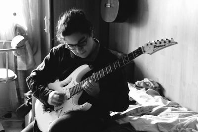 Teenage boy playing electric guitar at home