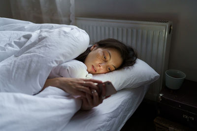Sad jealous girl sleepless in bed with smartphone scroll friend or ex-boyfriend social media photos
