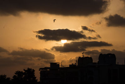 Silhouette buildings against sky during sunset