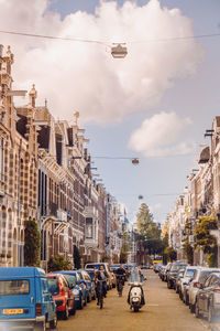 Cars on street by buildings against sky