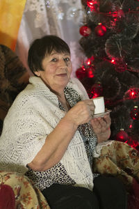 Midsection of man sitting by christmas tree