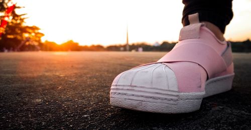 Low section of man legs against sky during sunset