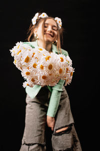 Happy woman holding flower against black background