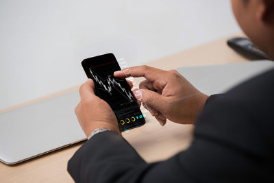 Midsection of man using mobile phone on table