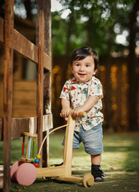 Full length of cute boy playing in park with a wooden  walker