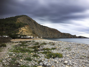 Scenic view of sea by mountain against sky