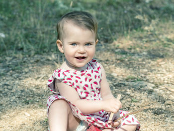 Portrait of baby girl smiling while sitting on field