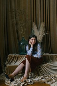 Young woman sitting on bed at home