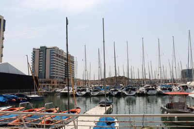 Boats moored at harbor against buildings in city