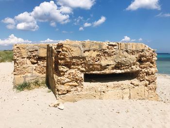 Stone wall on beach against sky