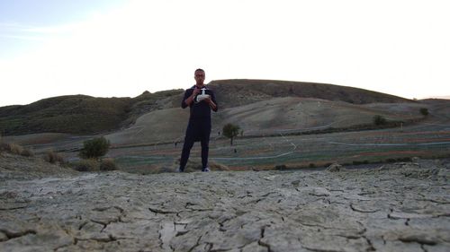 Rear view of man standing on mountain against sky