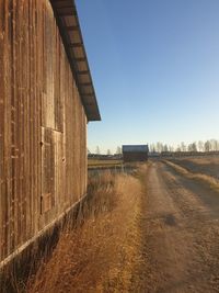 Road amidst field against clear sky