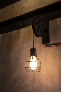 Low angle view of illuminated lamp on wall