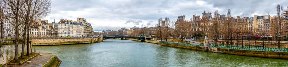 Bridge over river amidst buildings in city against sky