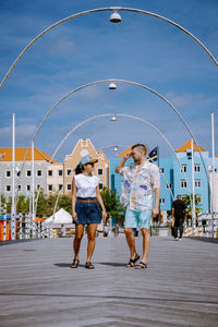 Rear view of people walking on umbrella against sky