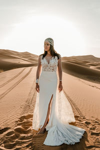 Woman standing on sand at beach against sky