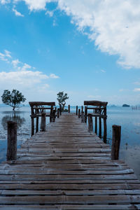 Wooden jetty on pier over sea against sky