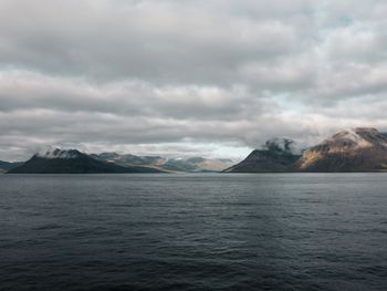 Scenic view of sea and mountain against cloudy sky