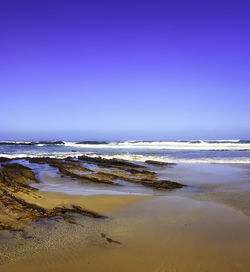 Scenic view of beach against clear blue sky