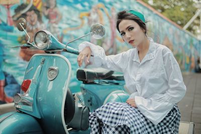 Portrait of young woman standing against car