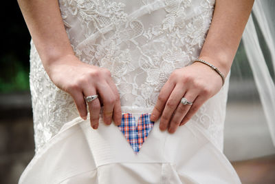 Midsection of bride holding sun hat with heart shape outdoors