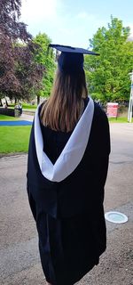 Rear view of woman wearing hat standing against trees