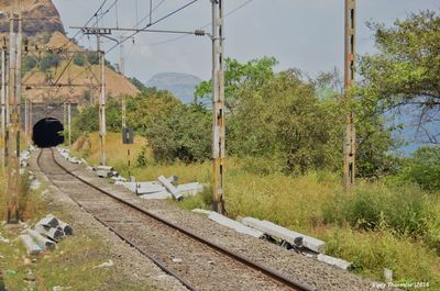Railroad track leading towards tunnel against sky