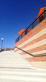 Steps by brick wall against clear blue sky