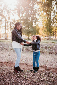 Mother and daughter holding hands standing at park