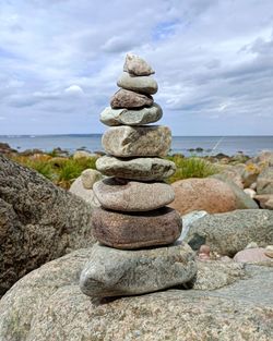 Stack of stones in sea against sky