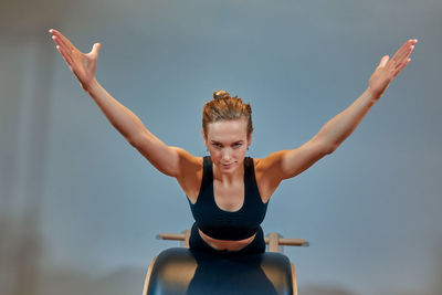 Portrait of young woman with arms raised