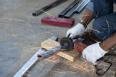 Low section of industrial worker cutting metal with hand saw