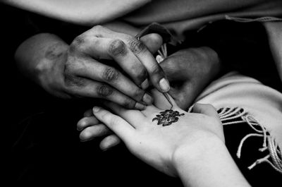 Close-up of woman receiving henna tattoo on hand