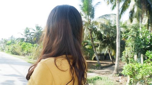 Rear view of woman standing against trees