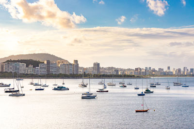 Sailboats and city buildings against sky  during sunset. tourism concept for rio de janeiro