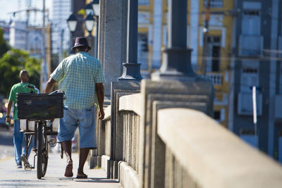 Rear view of men walking on street in city