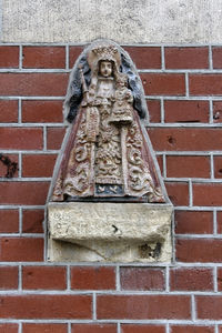 Low angle view of statue against brick wall