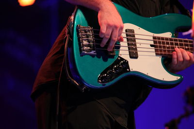 Midsection of man playing bass guitar