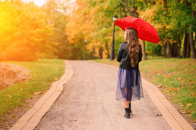 Rear view of woman with umbrella walking on road