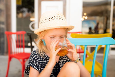 Cute girl drinking juice at outdoor restaurant