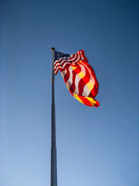 Low angle view of flag against clear blue sky