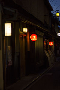 Illuminated street light against building at night